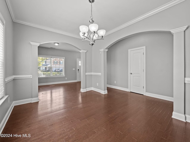 unfurnished dining area featuring wood finished floors, ornate columns, a notable chandelier, crown molding, and arched walkways