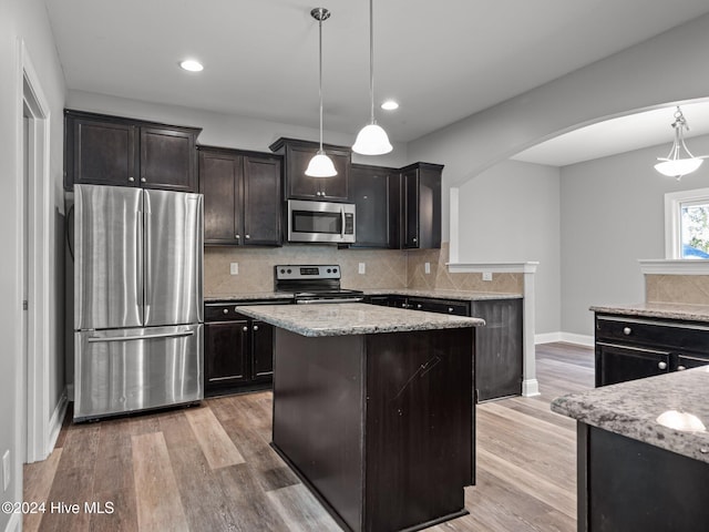 kitchen featuring a kitchen island, hanging light fixtures, stainless steel appliances, and light hardwood / wood-style floors