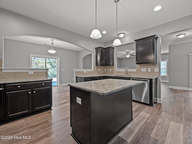 kitchen featuring dishwasher, sink, a center island, decorative light fixtures, and light wood-type flooring