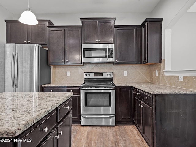 kitchen featuring pendant lighting, appliances with stainless steel finishes, light wood-type flooring, and decorative backsplash