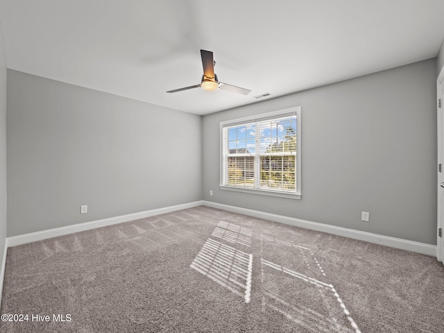 carpeted spare room featuring visible vents, baseboards, and ceiling fan