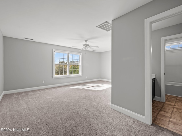 carpeted spare room featuring a ceiling fan, baseboards, a healthy amount of sunlight, and visible vents