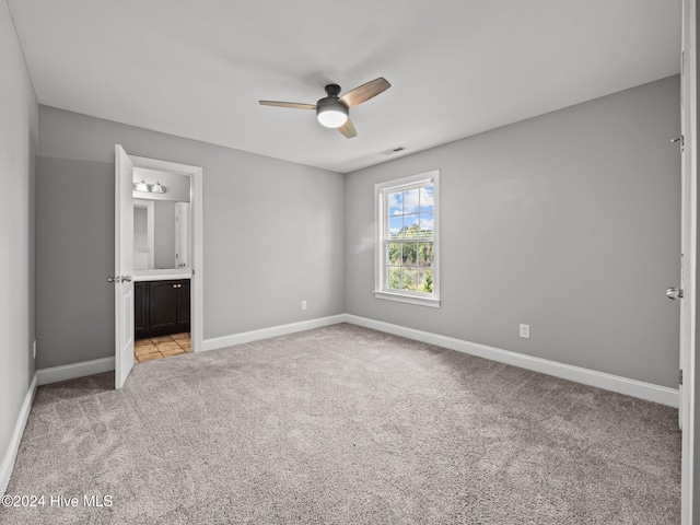 unfurnished bedroom with light colored carpet, ceiling fan, and ensuite bath