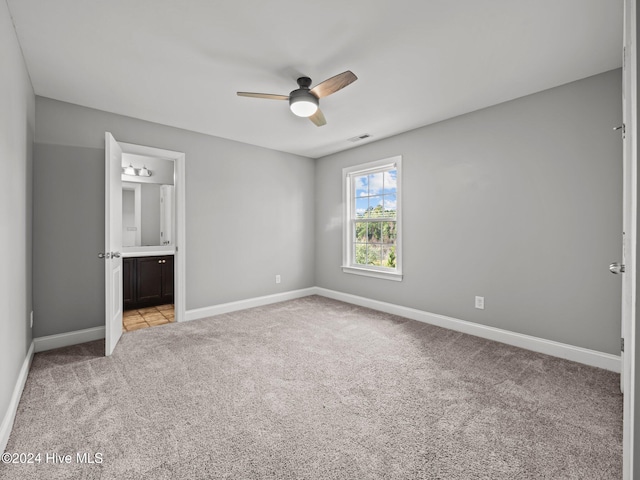 unfurnished bedroom with connected bathroom, light carpet, baseboards, and visible vents