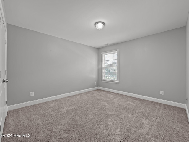 carpeted empty room featuring baseboards