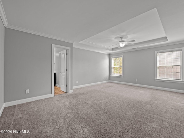 spare room featuring a tray ceiling, carpet flooring, baseboards, and ornamental molding