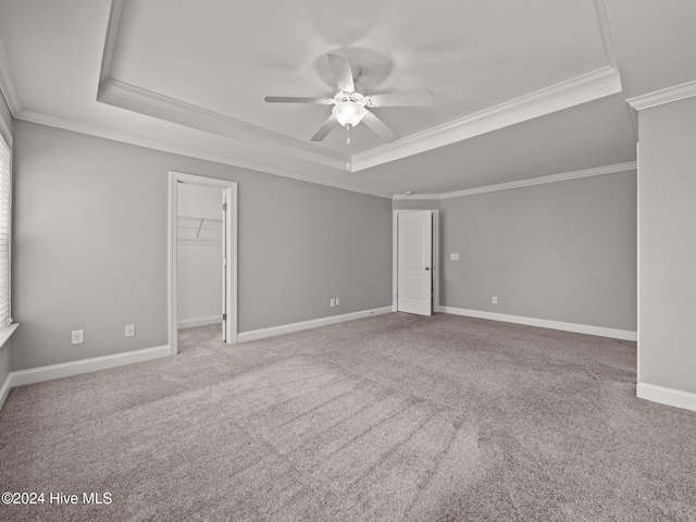 carpeted spare room with baseboards, a raised ceiling, ceiling fan, and crown molding