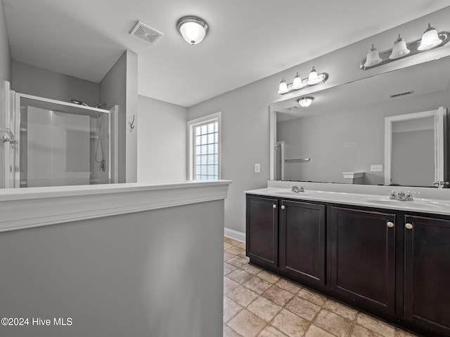 bathroom with double vanity, visible vents, a shower stall, and a sink