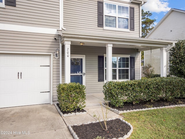 property entrance featuring covered porch and concrete driveway