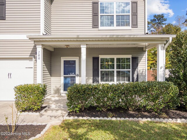 entrance to property with covered porch and an attached garage