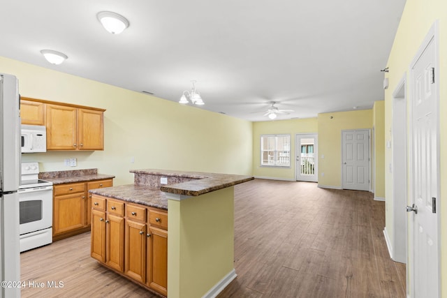 kitchen with white appliances, dark stone counters, a center island, and light wood-type flooring