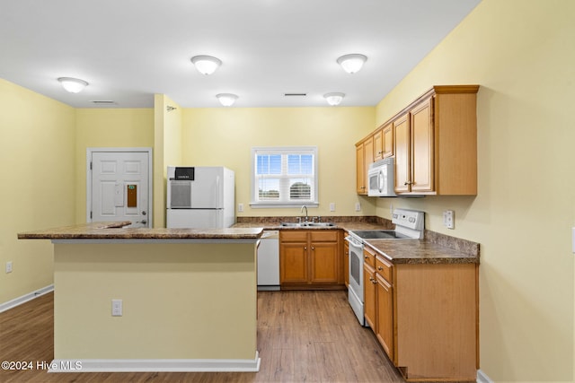 kitchen with sink, white appliances, light hardwood / wood-style flooring, and a kitchen island