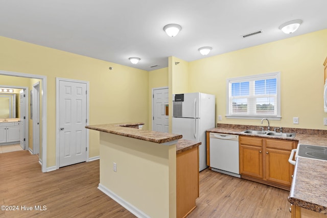 kitchen featuring white appliances, sink, a kitchen island, and light wood-type flooring