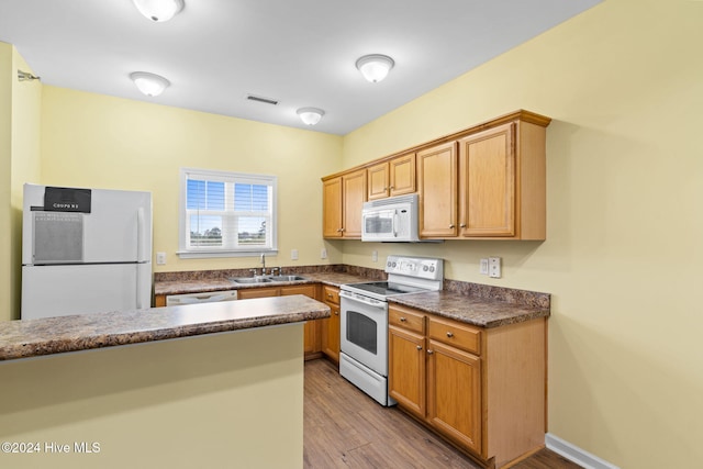 kitchen with sink, white appliances, and light hardwood / wood-style flooring