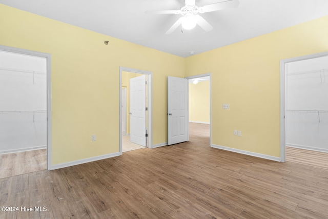 unfurnished bedroom featuring a walk in closet, a closet, and light hardwood / wood-style flooring