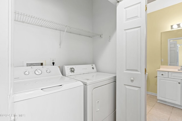 laundry area featuring washing machine and dryer, sink, and light tile patterned flooring