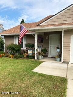 view of front of house with a garage, covered porch, and a front lawn