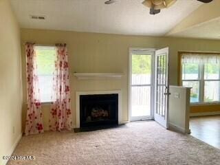 unfurnished living room with carpet floors, plenty of natural light, lofted ceiling, and ceiling fan