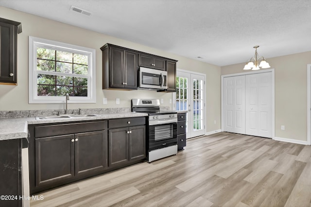 1912 Paulette Rd, Morehead City, NC 28557 - kitchen featuring appliances with stainless steel finishes, a sink, light countertops, light wood-style flooring, and a textured ceiling
