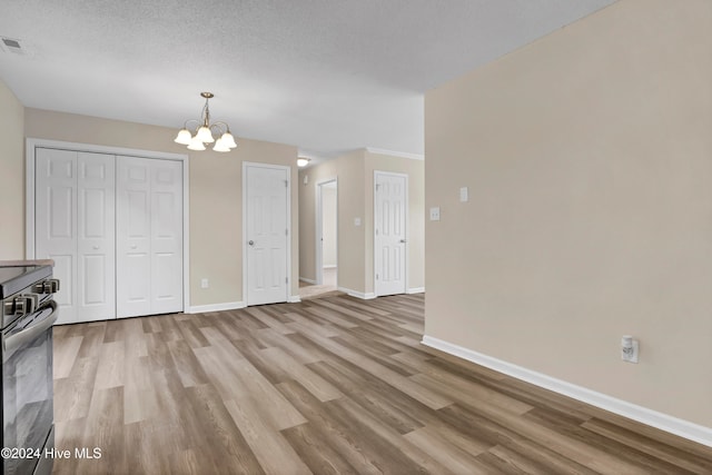 interior space with an inviting chandelier, a textured ceiling, and light hardwood / wood-style floors