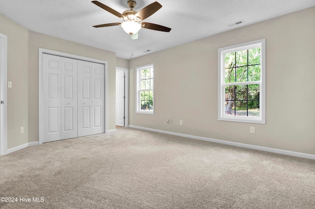 unfurnished bedroom featuring carpet, multiple windows, and ceiling fan