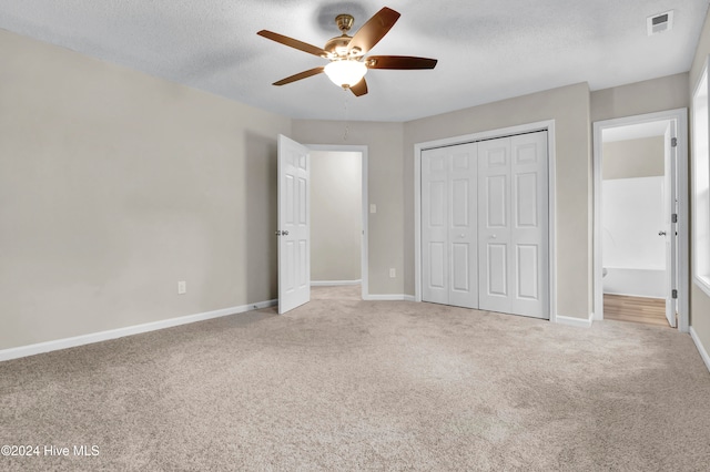 unfurnished bedroom featuring carpet, a textured ceiling, a closet, and ceiling fan