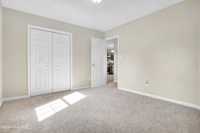 unfurnished bedroom with light colored carpet and a closet