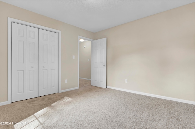 unfurnished bedroom with a textured ceiling, carpet floors, and a closet