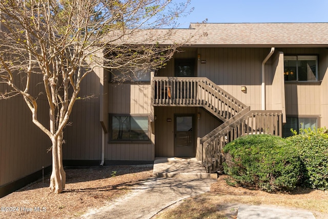 exterior space with stairway and roof with shingles