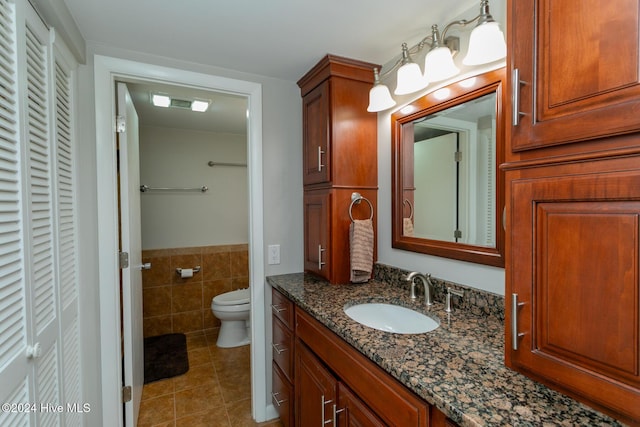 bathroom featuring tile walls, a closet, toilet, tile patterned flooring, and vanity