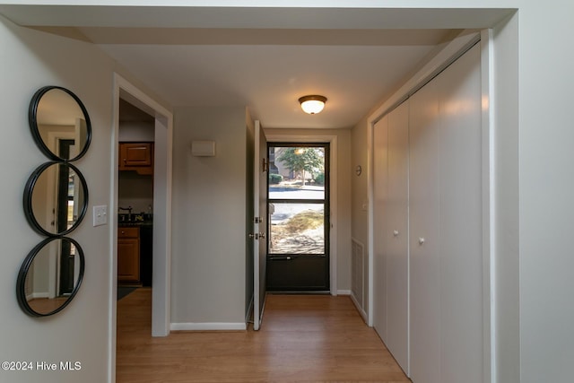 doorway with light wood-style flooring, baseboards, and visible vents