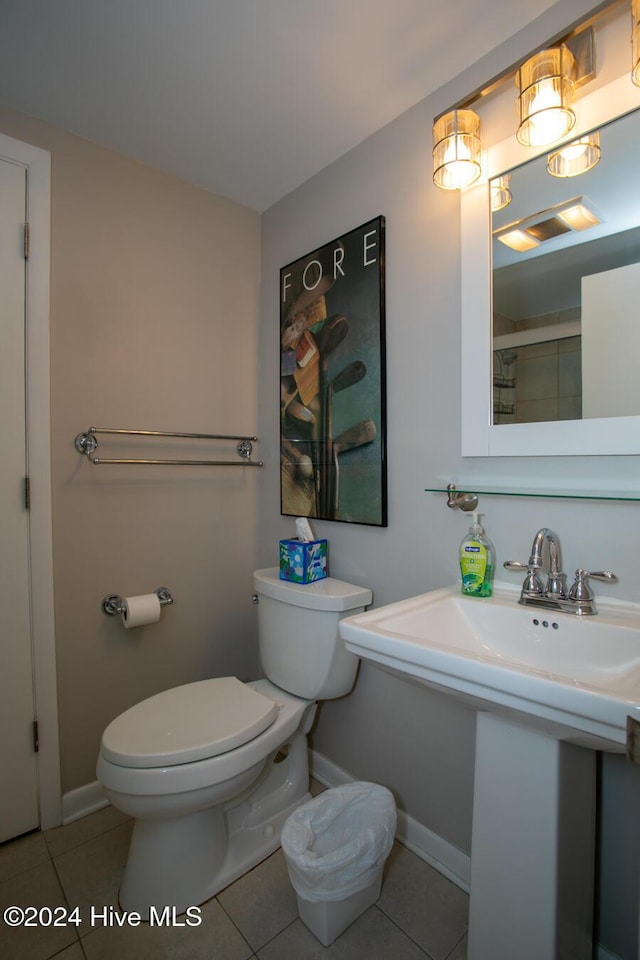 bathroom featuring tile patterned flooring, toilet, baseboards, and a tile shower
