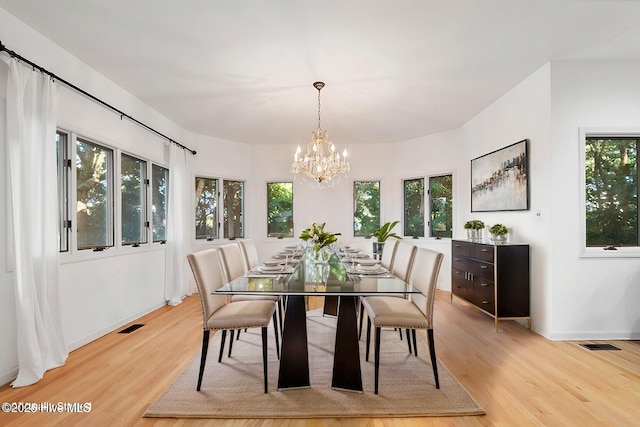 dining room with plenty of natural light, light hardwood / wood-style flooring, and a notable chandelier