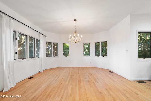 spare room featuring an inviting chandelier and light wood-type flooring