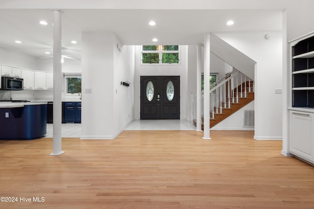 entryway with a towering ceiling, a wealth of natural light, and light hardwood / wood-style flooring