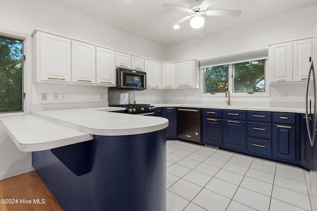 kitchen featuring sink, black appliances, white cabinets, and blue cabinetry