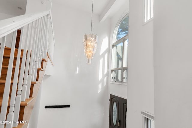 stairs with beam ceiling and a chandelier