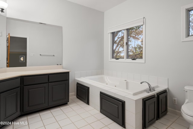 bathroom with tile patterned flooring, vanity, a relaxing tiled tub, and toilet