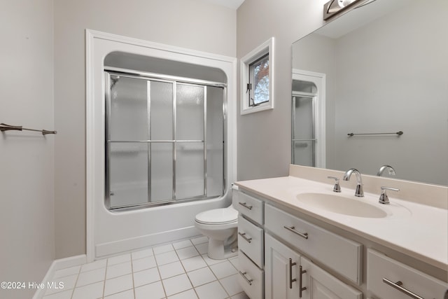 full bathroom with tile patterned flooring, vanity, bath / shower combo with glass door, and toilet