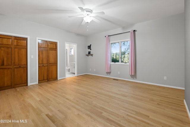 unfurnished bedroom with ensuite bathroom, two closets, ceiling fan, and light hardwood / wood-style flooring