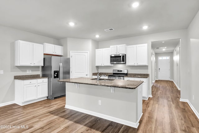 kitchen with light hardwood / wood-style floors, stainless steel appliances, a center island with sink, and white cabinets