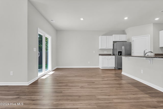 kitchen featuring stainless steel fridge, white cabinets, hardwood / wood-style flooring, and sink