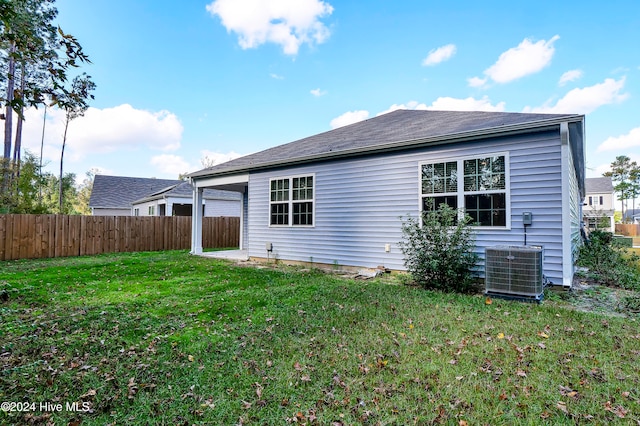 rear view of house with cooling unit and a lawn