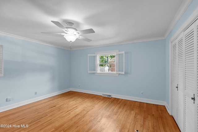 unfurnished bedroom featuring wood-type flooring, ceiling fan, crown molding, and a closet