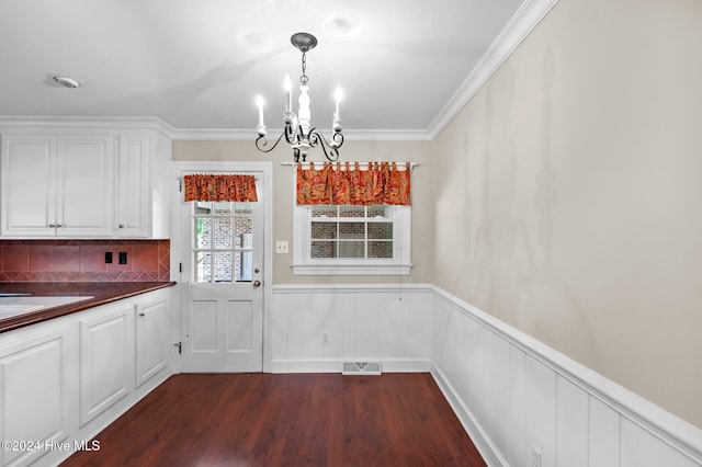 unfurnished dining area with dark hardwood / wood-style floors, ornamental molding, and a notable chandelier