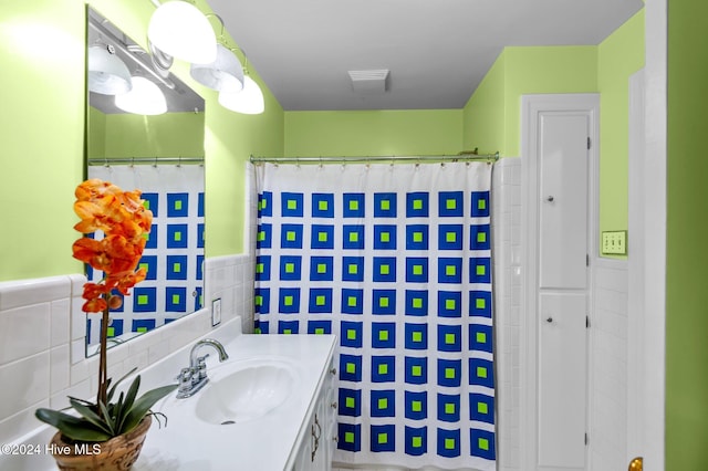 bathroom with walk in shower, vanity, and tile walls