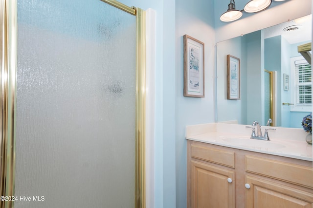 bathroom featuring a shower with shower door and vanity