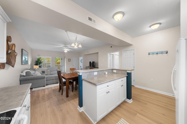 kitchen featuring white cabinetry, white refrigerator with ice dispenser, ceiling fan with notable chandelier, and light wood-type flooring