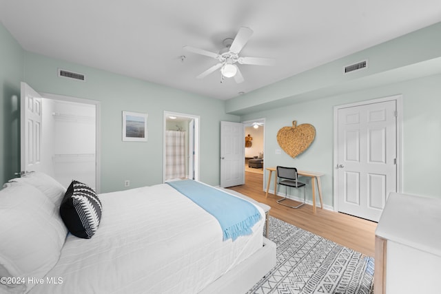 bedroom featuring a closet, wood-type flooring, a walk in closet, and ceiling fan