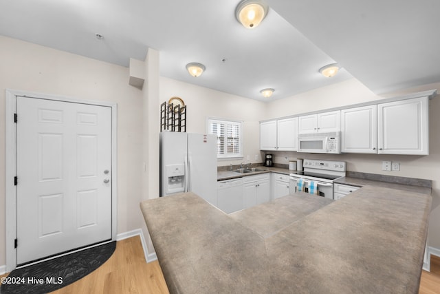 kitchen with white appliances, sink, kitchen peninsula, light hardwood / wood-style floors, and white cabinets